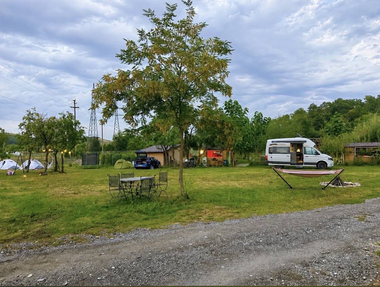 Zelte, ein Auto und ein Wohnmobil auf der Wiese, mit Hängematte und Feuerstelle