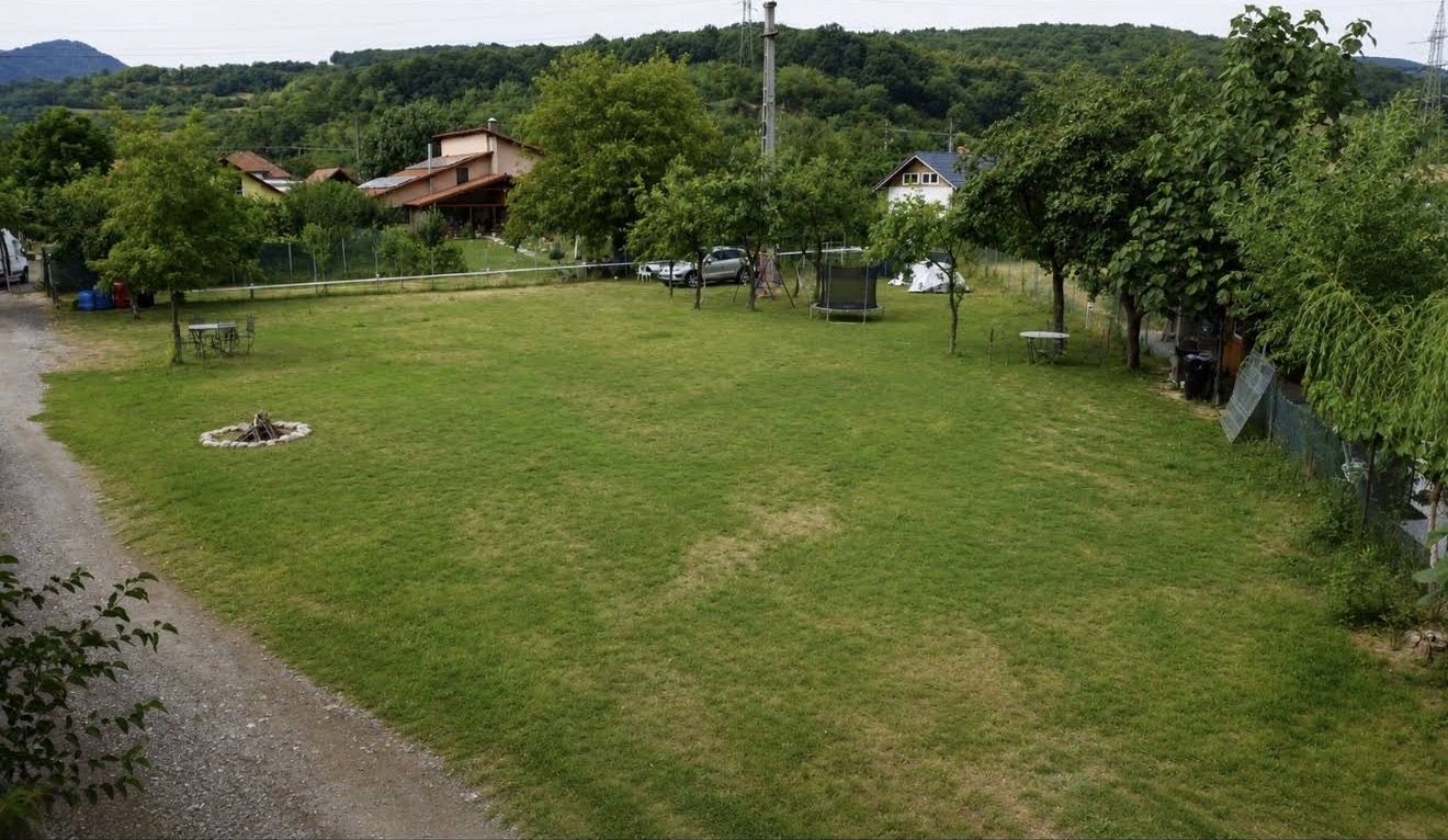 Die weite Wiese des Campingplatzes, mit Feuerstelle, Tischen und Bäumen