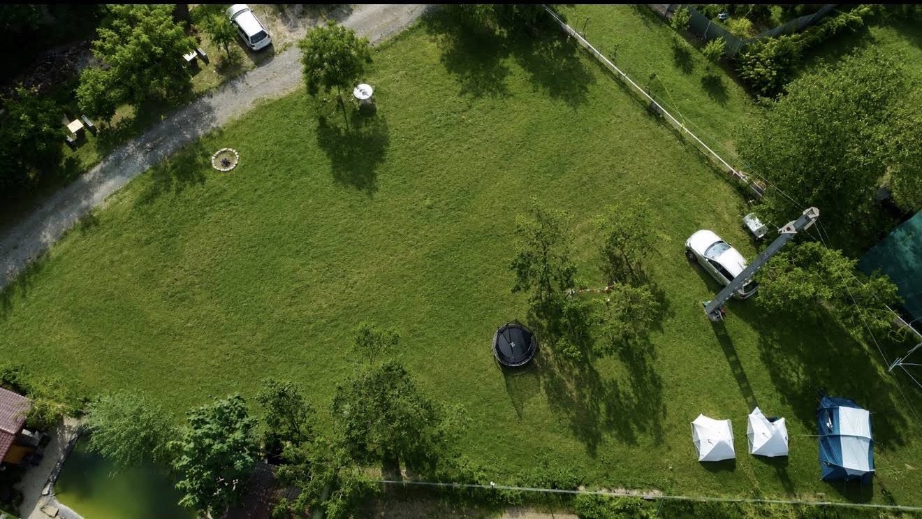 Die Wiese des Campingplatzes aus der Drohnenperspektive, mit Zelten, Trampolin und Zufahrt